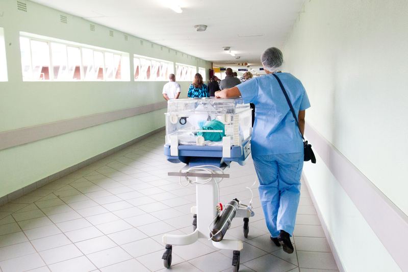 Nurse with neonatal incubator in a hospital corridor